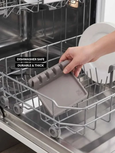Hand placing a thick, dishwasher safe silicone spoon pad into the rack, serving as an easy to clean stove top protector mat.