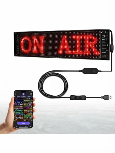 Smartphone controlling a red ON AIR Bluetooth app control LED advertising board via USB cable.
