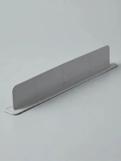 Grey flexible silicone water stopper for kitchen counter with a flat base and suction cups for easy setup.
